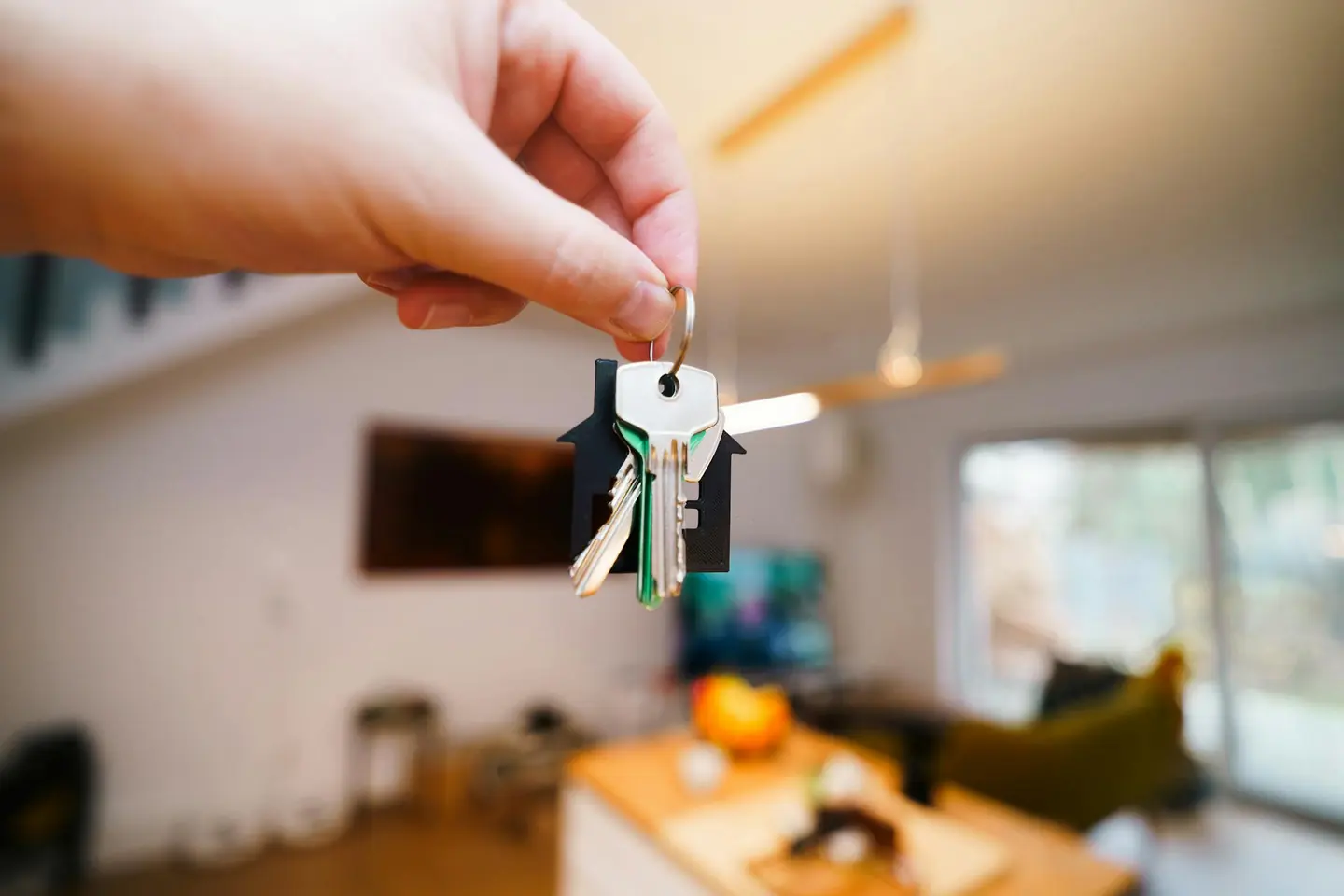 A set of house keys held up in a bright living room