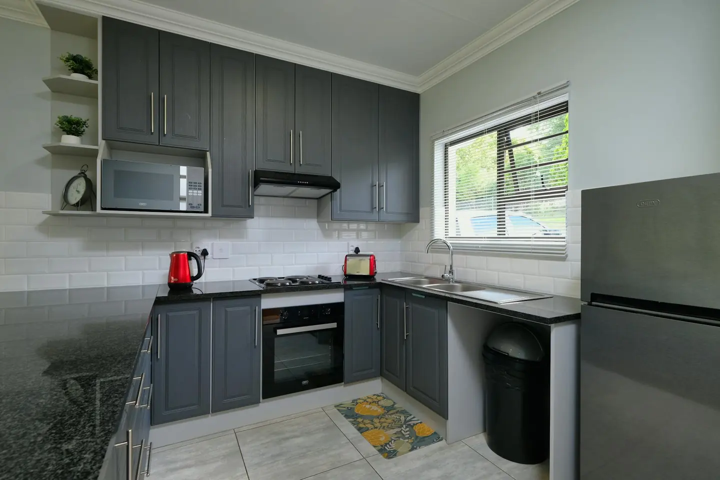 A fitted kitchen with dark grey cabinets and stainless steel appliances